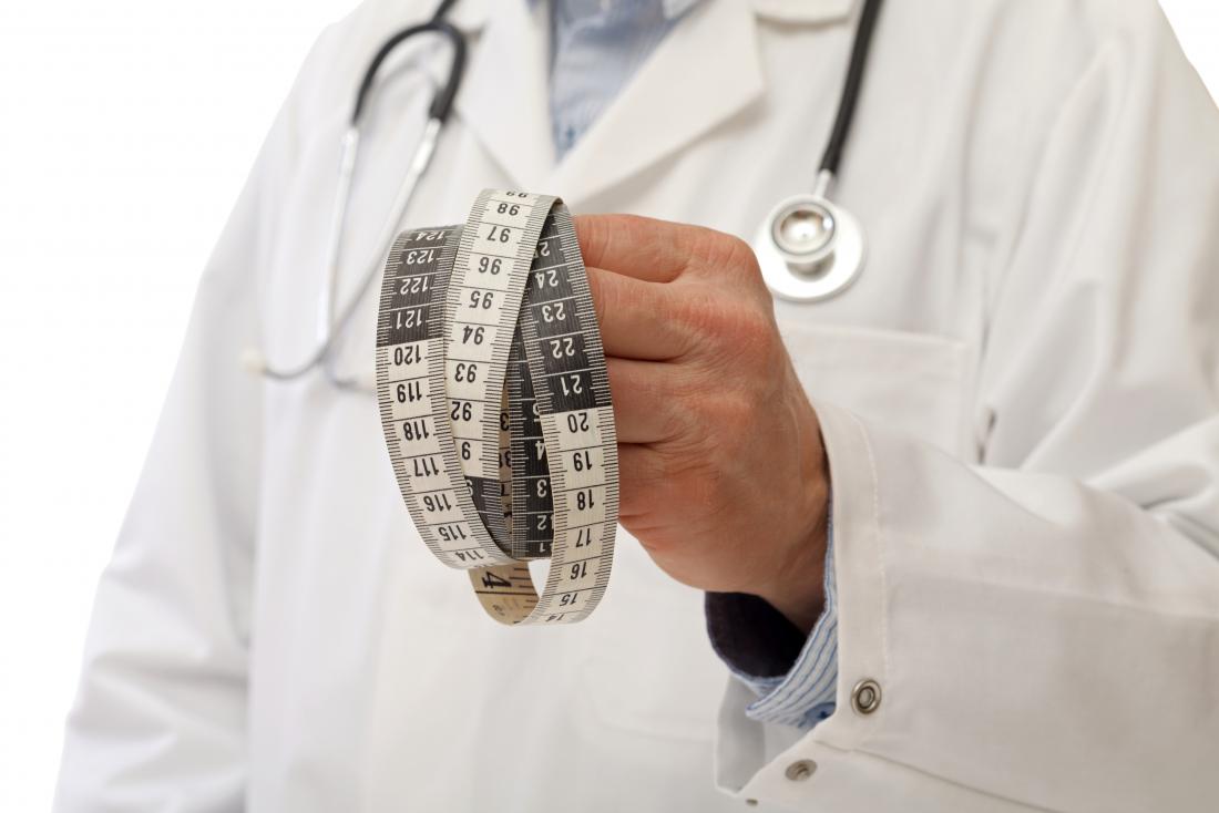 A doctor holding a tape measure to measure visceral fat
